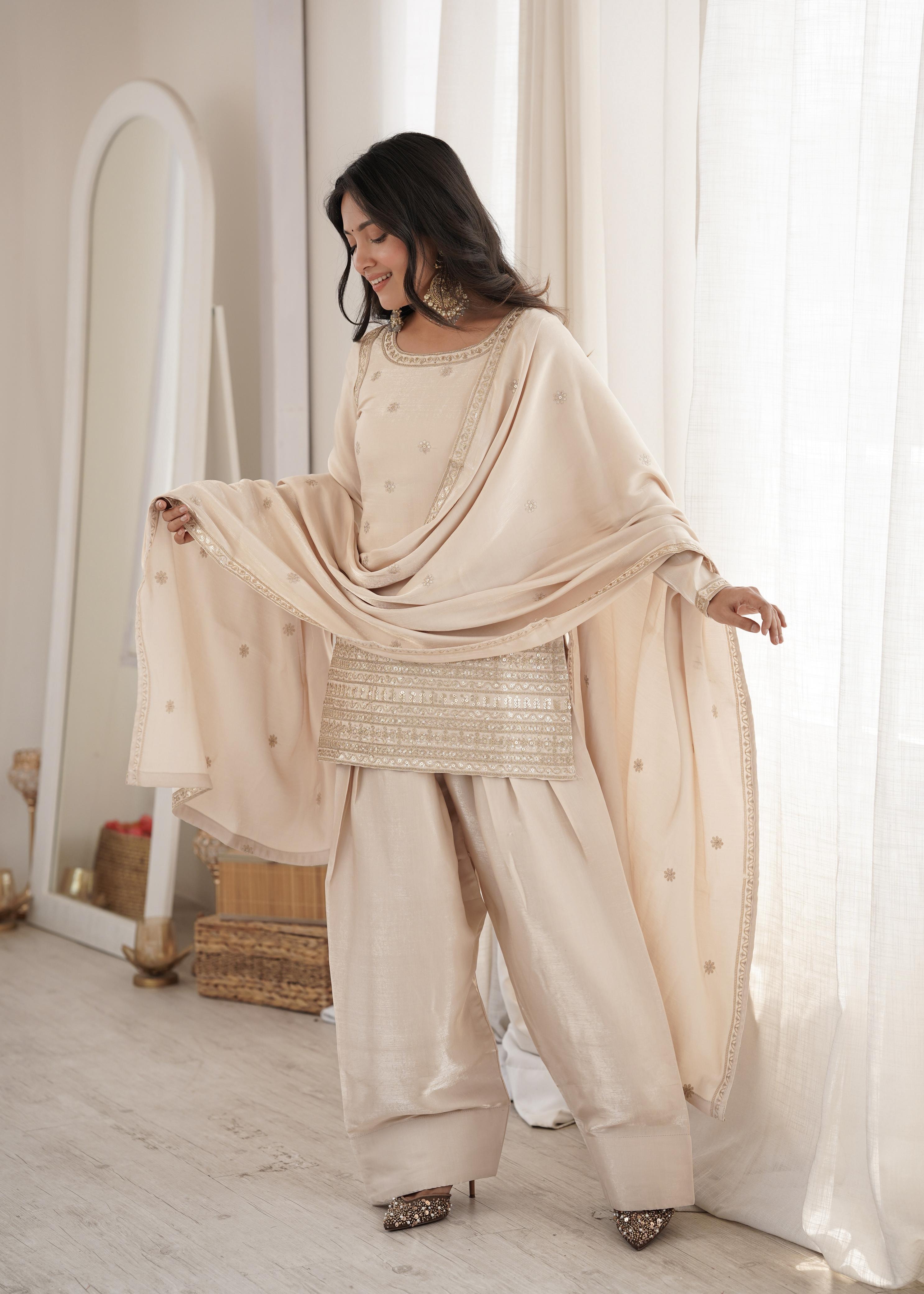 Model posing in cream glass roman silk suit set near window