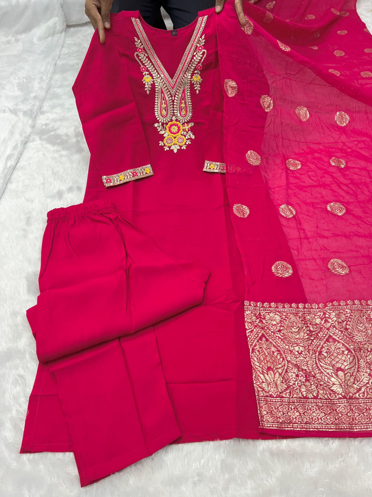 Flat lay close-up of rani pink kurti showing V-neck embroidery and sequence work