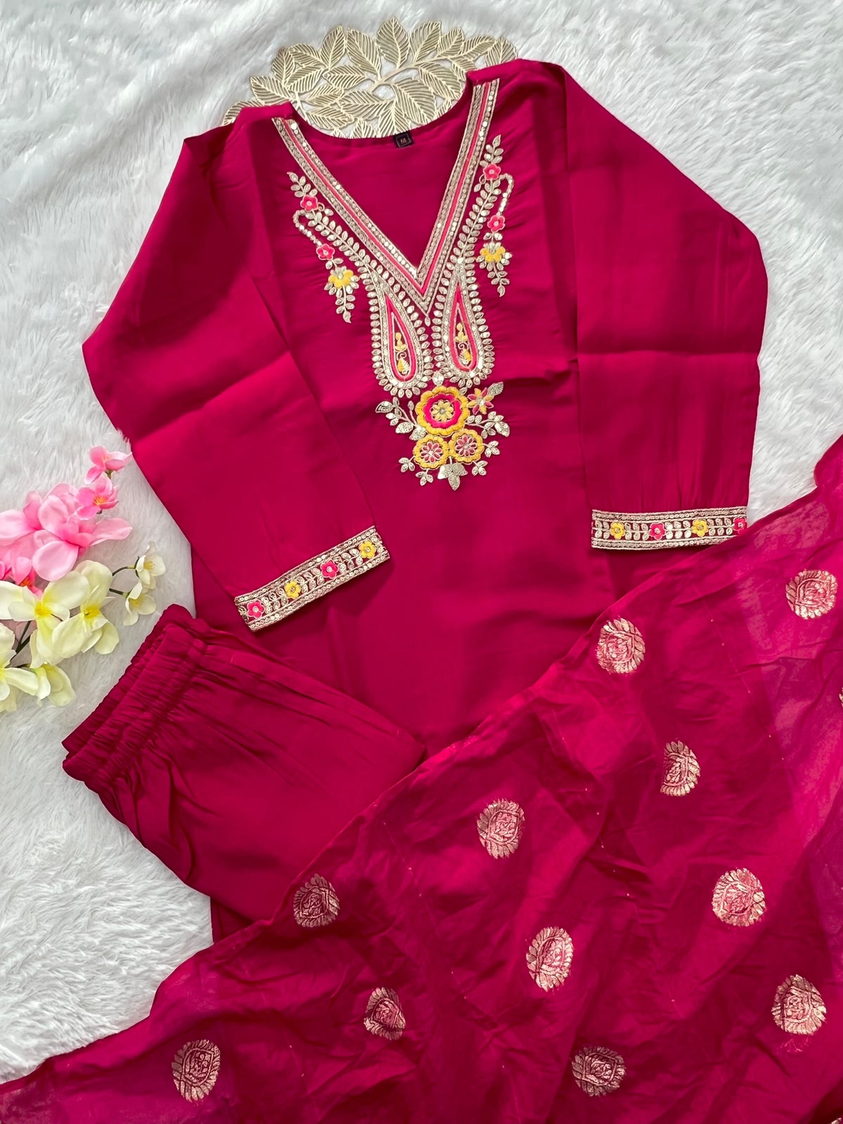 Flat lay of rani pink kurti with embroidered cuffs and zari dupatta with buti