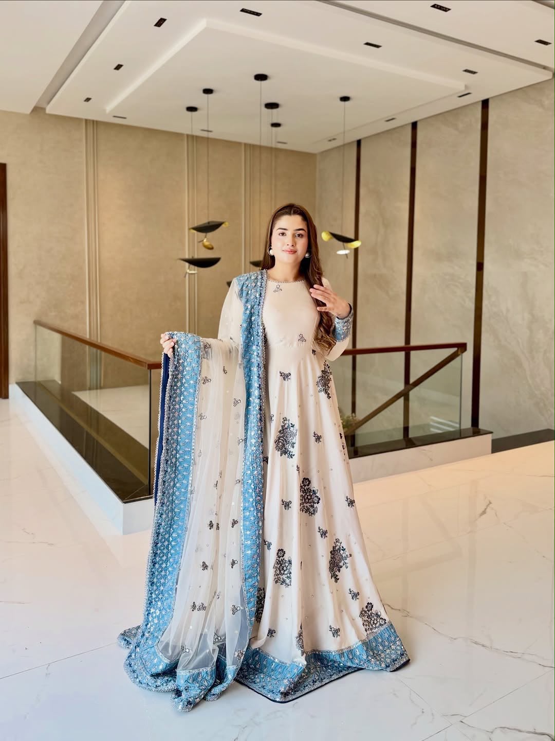 Model in ivory embroidered gown holding sky blue organza dupatta full length view