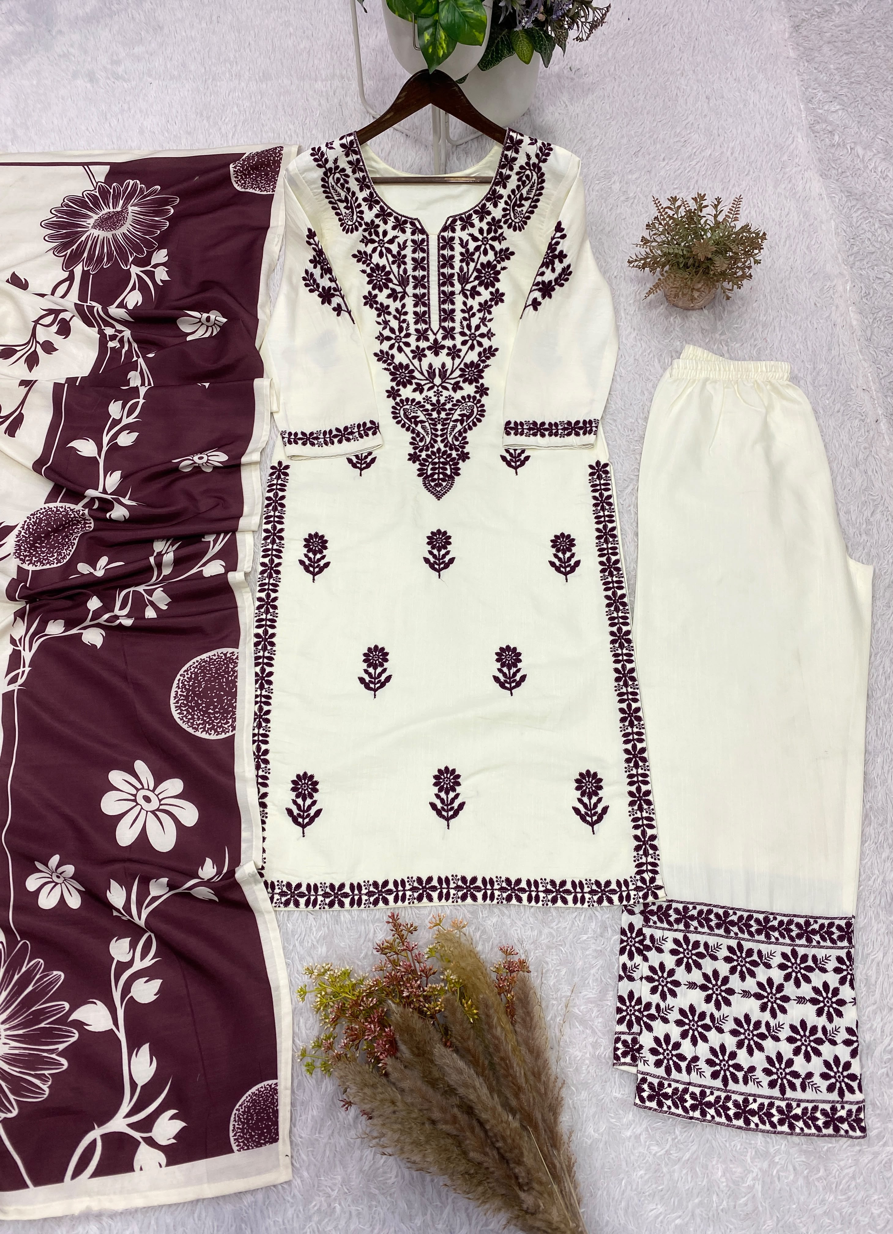 Model wearing white embroidered suit set with black dupatta taking mirror selfie in boutique