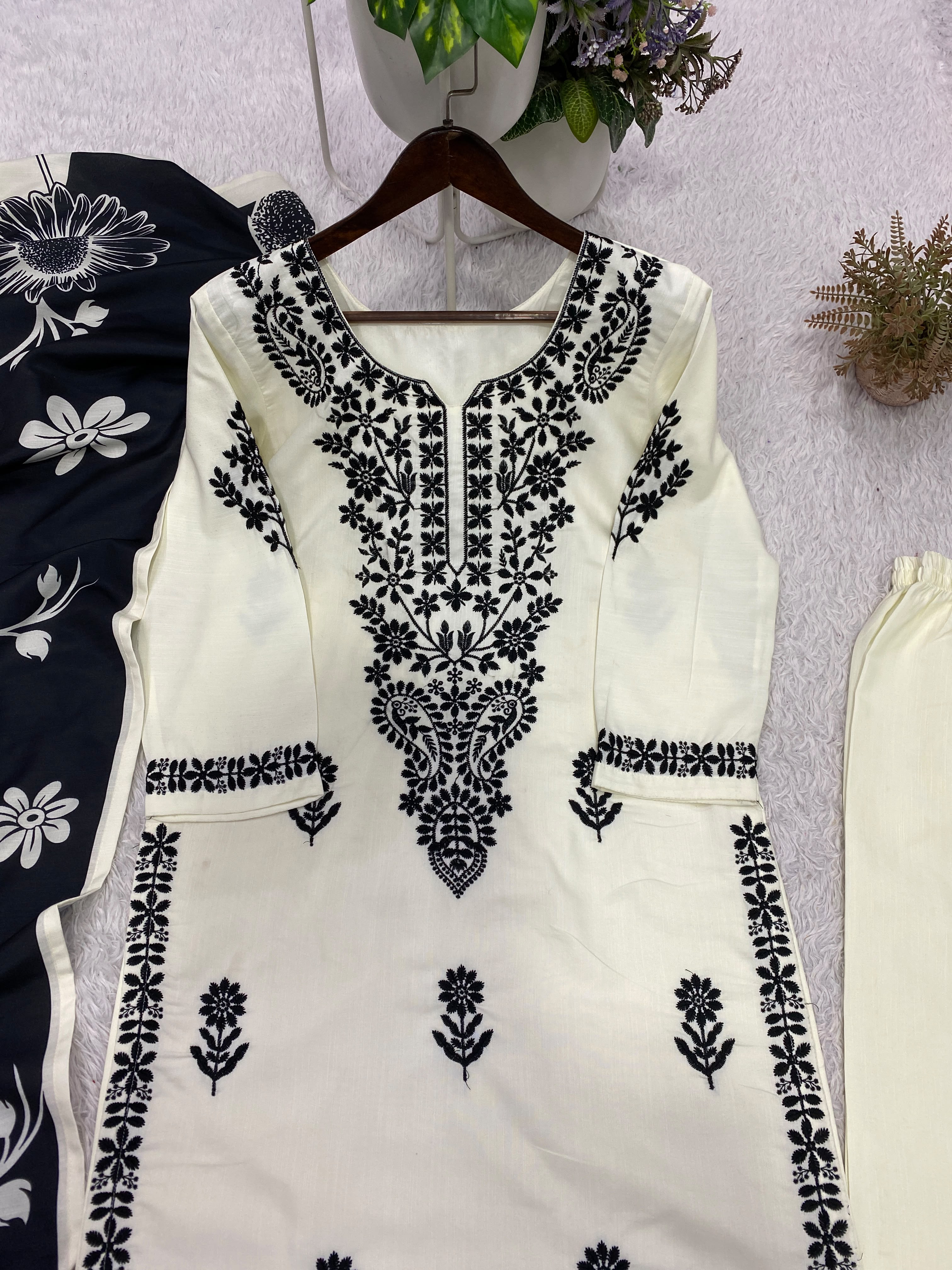 Flat lay of white embroidered kurta with black dupatta showing complete suit set
